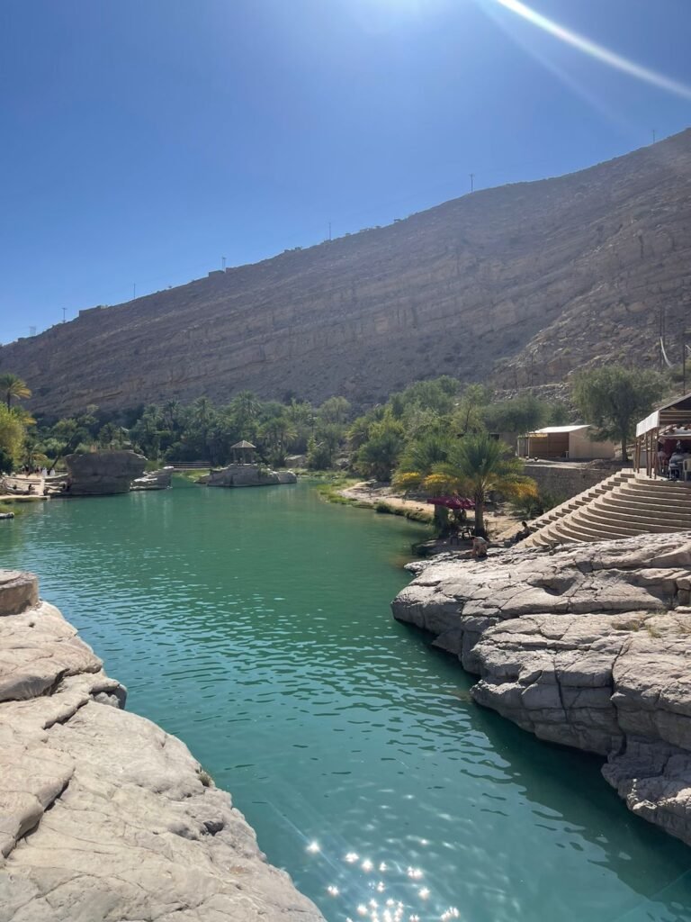  The vibrant emerald-green natural pools of Wadi Bani Khalid surrounded by rocky cliffs and palm trees in Oman.