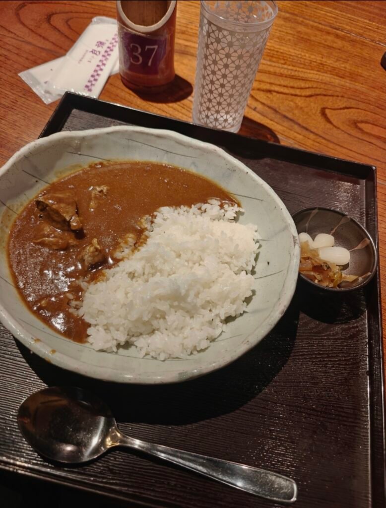 A PALTE OF CLASSIC JAPANESE CURRY WITH WHITE RICE ON A WOODEN TABLE SETTING 