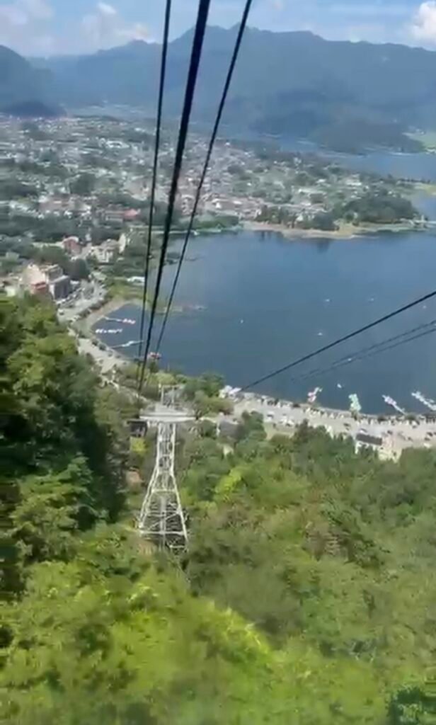 Ropeway cable car descending towards Lake Kawaguchiko with scenic mountain views.