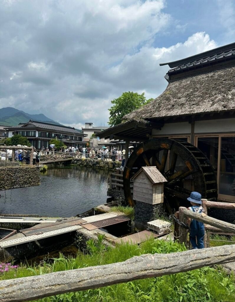 Traditional thatched-roof house with a wooden waterwheel by a clear pond in Oshino Hakkai near Mount Fuji.