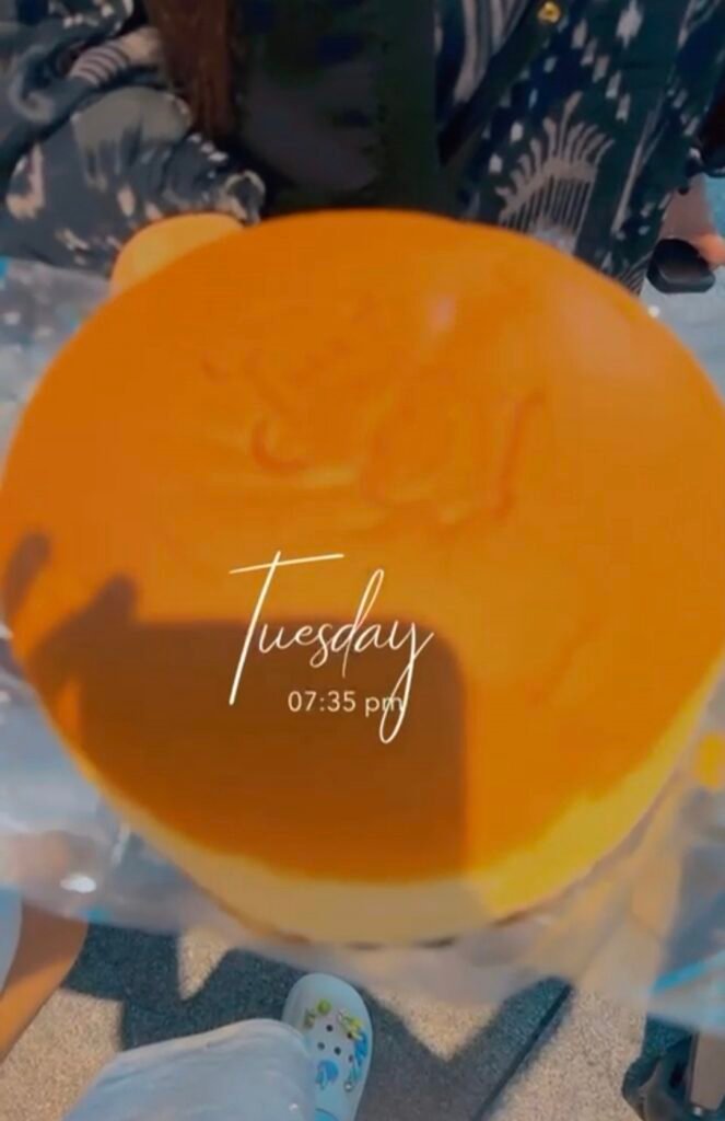 FRESHLY BAKED ROUND RIKURO OJISAN JAPANESE SOUFFLE CHEESECAKE HELD IN PLASTIC WRAPPER IN OSAKA 