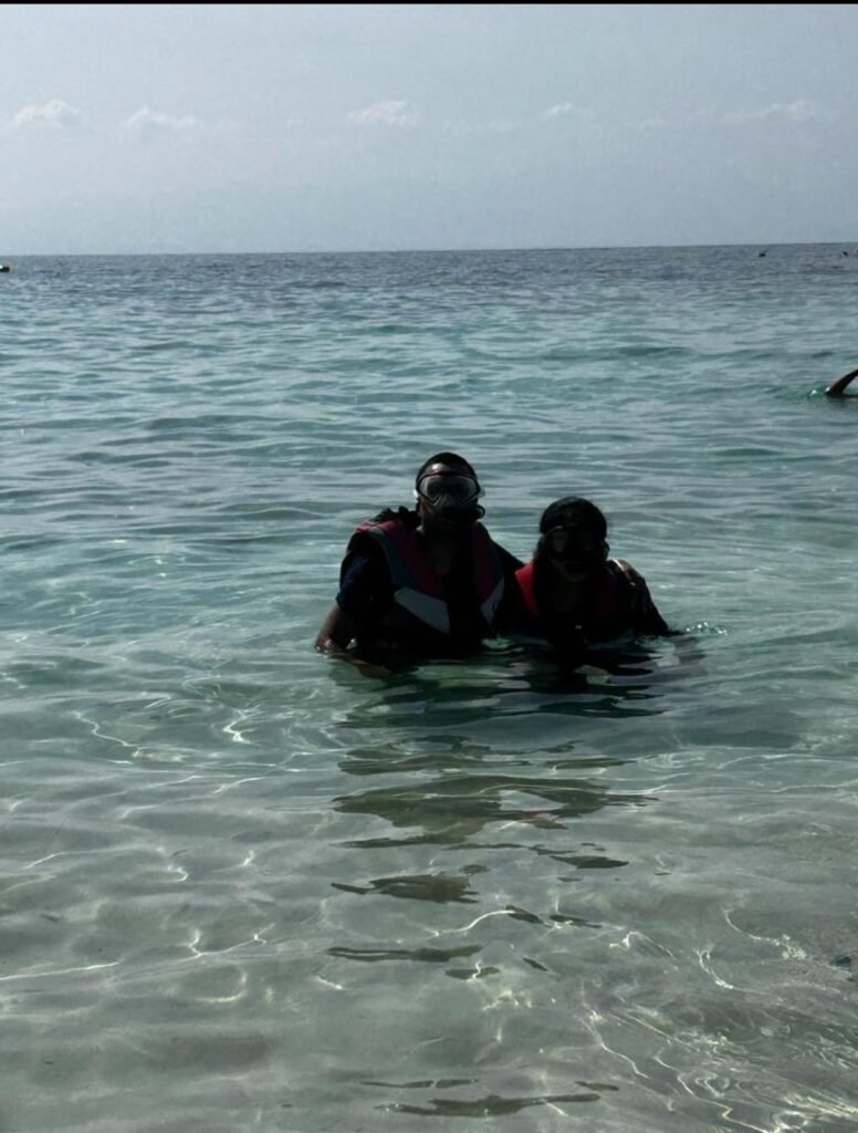 Two travelers wearing life jackets and snorkeling masks standing in the clear turquoise ocean water in Oman.