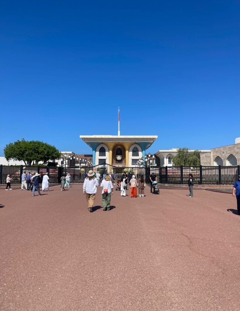 Tourists walking toward the colorful facade of Al Alam Palace, the ceremonial palace of Sultan Qaboos in Muscat, Oman.