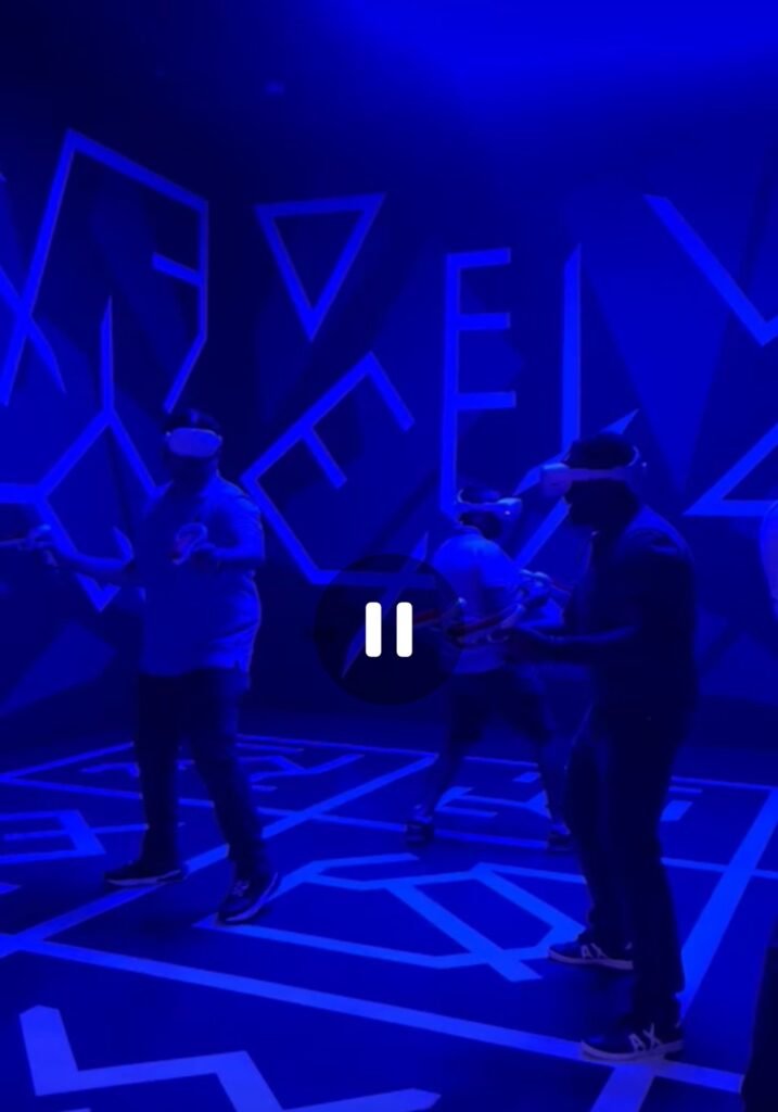 Travelers wearing VR headsets experiencing an interactive virtual reality game under blue neon lights in Oman.